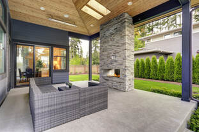 Outdoor concrete patio area with fireplace and furniture for seating